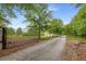 Gated gravel driveway leading to a home surrounded by mature trees and landscaping at 300 Massengale Rd, Brooks, GA 30205