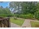Green backyard with a wooden bench and a paved walkway, surrounded by mature trees and shrubbery at 4457 Huntshire Dr, Stone Mountain, GA 30083