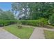 Green backyard with a wooden bench and a paved walkway, surrounded by mature trees and shrubbery at 4457 Huntshire Dr, Stone Mountain, GA 30083