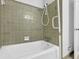 Bathroom featuring white tub, shower, grab bar and green tile at 4457 Huntshire Dr, Stone Mountain, GA 30083