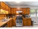 Classic kitchen featuring wood cabinetry, stainless steel appliances, and a light-filled window at 2469 Silver King Dr, Grayson, GA 30017