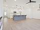 Open-concept living area with wood floors, modern kitchen island, pendant lights, and stainless steel appliances at 4663 Larkfield Way, Powder Springs, GA 30127