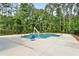 Outdoor community pool with easy-access lift surrounded by spacious concrete deck and bordered by trees and black metal fence at 4663 Larkfield Way, Powder Springs, GA 30127