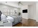 Well-lit staged bedroom with hardwood floors, TV, grey comforter, and large windows at 2616 Boddie Pl, Duluth, GA 30097