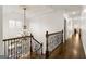 This expansive hallway features gleaming hardwood floors, decorative chandelier and wood railing at 2616 Boddie Pl, Duluth, GA 30097