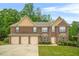 Charming brick two-story home boasts a three-car garage, manicured lawn, and lush landscaping at 4616 Town Manor Dr, Douglasville, GA 30135