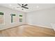 Bright living room featuring a modern ceiling fan, three large windows, and light wood flooring at 4667 Larkfield Way, Powder Springs, GA 30127