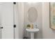 Stylish powder room with pedestal sink, oval mirror, and neutral colors at 4667 Larkfield Way, Powder Springs, GA 30127