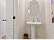 Stylish powder room featuring pedestal sink, oval mirror, gold fixtures, and modern finishes at 4667 Larkfield Way, Powder Springs, GA 30127