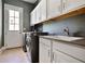 Functional laundry room featuring a sink, cabinets, and modern washer and dryer units at 5335 Briarstone Ridge Way, Alpharetta, GA 30022