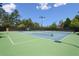 Outdoor tennis courts featuring blue and green surfaces, lighting, and surrounding greenery at 5335 Briarstone Ridge Way, Alpharetta, GA 30022