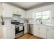 Modern kitchen with white cabinets, stainless steel appliances, and bright natural light from the window at 780 Old Magnolia Trl, Canton, GA 30115