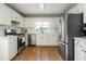 Modern kitchen with stainless steel appliances, white cabinetry, subway tile backsplash, and wood floors at 780 Old Magnolia Trl, Canton, GA 30115