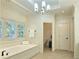 Bright bathroom featuring a soaking tub, tile floors, large windows, and a stylish light fixture at 1632 Brookhaven Close Ne, Atlanta, GA 30319