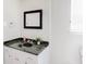 Bathroom features a sleek vanity with black granite countertop and dark framed mirror at 8451 Magnolia Dr, Jonesboro, GA 30238
