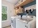 Charming laundry room with a large window, overhead shelves, and modern washer and dryer at 10090 Feather Sound Ct, Alpharetta, GA 30022