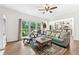 Living room featuring a comfortable green sofa, hardwood floors, and large windows overlooking the backyard at 10090 Feather Sound Ct, Alpharetta, GA 30022