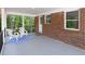 Inviting back porch with brick wall, seating, blue rug, and wooded view at 1140 Starline Se Dr, Smyrna, GA 30080