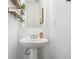 Compact powder room featuring a pedestal sink, decorative mirror, and modern wall shelves at 1560 Avalon Creek Rd, Sugar Hill, GA 30518