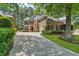 Exterior view of the brick home with long driveway, mature trees, and well-maintained landscaping at 5303 Davenport Mnr, Cumming, GA 30041