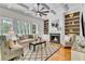 Cozy living room with a fireplace, built-in bookshelves, hardwood floors, and coffered ceilings at 5303 Davenport Mnr, Cumming, GA 30041
