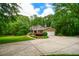 Charming brick home featuring a two-car garage, lush landscaping, and a spacious concrete driveway under a partly cloudy sky at 110 Sandy Ridge Trl, Fayetteville, GA 30214
