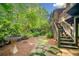 Charming backyard featuring a stone path, lush greenery, and wooden stairs leading to the upper deck at 2144 Lamplight Dr, Marietta, GA 30062