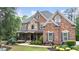 Charming two-story brick home with stone accents, covered front porch, and manicured landscaping at 5475 Copper Creek Pass, Cumming, GA 30040