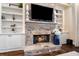 Close up of the stone fireplace with built-in shelving and a large TV, with visible gas logs burning at 5475 Copper Creek Pass, Cumming, GA 30040