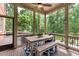 Outdoor screened porch with wooden table, bench seating, and peaceful views of the backyard at 5475 Copper Creek Pass, Cumming, GA 30040