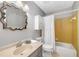 Bright bathroom featuring a decorative mirror, single sink vanity, toilet, and bathtub with a shower curtain at 203 Concorde Sw Way, Lilburn, GA 30047
