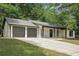 View of the house with a two-car garage, stone accents, and a well-maintained lawn at 250 Huntcliff Ct, Fayetteville, GA 30214
