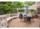 Back deck with table, chairs, grill, and bench. Surrounded by white rails and green trees at 3115 Peachtree Ne Dr, Atlanta, GA 30305