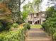 The tiered backyard has lush landscaping, multiple levels, stairs, and a charming two-story home in the background at 3115 Peachtree Ne Dr, Atlanta, GA 30305