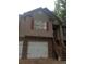 A front view of a two-story home with tan siding, brick facade, red shutters, and white garage door at 143 Delane Dr, Dallas, GA 30157
