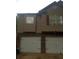 A view of two-car garage with white doors and dark handles on a two-story home with tan siding at 143 Delane Dr, Dallas, GA 30157