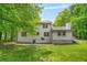 Well-maintained backyard with mature trees, a lush lawn, and a two-story house with a white exterior at 230 Deer Forest Rd, Fayetteville, GA 30214