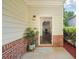 Inviting front porch with brick accents, a stylish light fixture, and a view into the living area at 6071 Apple Grove Rd, Buford, GA 30519