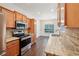 Bright kitchen featuring stainless steel appliances, light wood cabinets, and an adjacent dining area at 6071 Apple Grove Rd, Buford, GA 30519