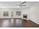 Bright living room with hardwood floors, stone fireplace, large windows, and modern ceiling fan at 6071 Apple Grove Rd, Buford, GA 30519