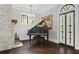 Stylish living room featuring a black grand piano near a stone fireplace and bright windows at 908 N Highland Ne Ave, Atlanta, GA 30306