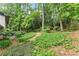 Lush backyard with a well-maintained lawn, mature trees, and a gravel path leading to the home's patio at 1190 Hess Dr, Avondale Estates, GA 30002