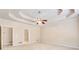 Spacious main bedroom featuring a tray ceiling, ceiling fan, carpet and access to the bathroom at 2417 Saint Feagin Pl, Powder Springs, GA 30127
