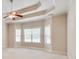 Spacious main bedroom featuring a tray ceiling, ceiling fan, carpet and large windows at 2417 Saint Feagin Pl, Powder Springs, GA 30127