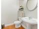 Stylish half bathroom with a pedestal sink, hardwood flooring, and modern fixtures at 525 Roland Manor Dr, Dacula, GA 30019