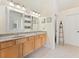 Bright bathroom featuring double sinks, wood cabinets, tile floors, and decorative shelving at 525 Roland Manor Dr, Dacula, GA 30019