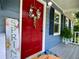 Charming entrance featuring a red door adorned with a floral wreath, complemented by blue siding and a Spring sign at 5364 Muirwood Pl, Powder Springs, GA 30127