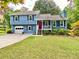 Charming blue split-level home featuring a red front door and well-maintained landscaping at 5364 Muirwood Pl, Powder Springs, GA 30127