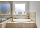 Close up of a bathtub surrounded by tile, with a window and decor at 209 Wynnward Way, Sharpsburg, GA 30277