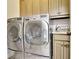 Laundry room with stainless steel washer and dryer, custom wood cabinets and a granite countertop folding station at 209 Wynnward Way, Sharpsburg, GA 30277